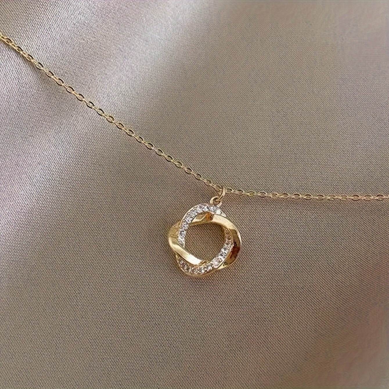 Elegantní zlatý náhrdelník s visacími prvky a simulovanými diamanty
